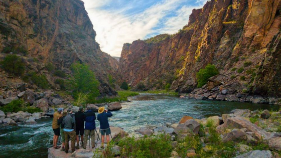 a group of people on a rock next to a body of water